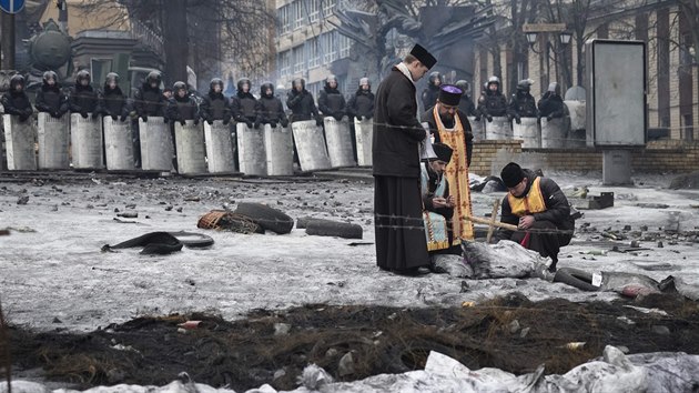 Pravoslavn kn zapaluj svky ped kordonem policist v centru hlavnho msta (13. nora 2014).