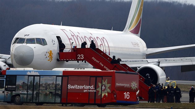 Cestujc s rukama za hlavou za dohledu policie opoutj letadlo, kter unesl etiopsk kopilot (17. nora 2014).