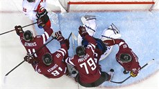 Lotytí hokejisté brání svého gólmana Kristerse Gudlevskise. (19. února 2014)