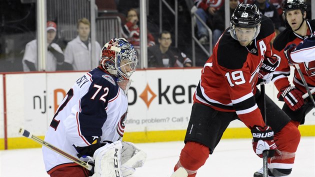 LIK.  Travis Zajac  Z New Jersey zkou pelstt branke Columbusu. Sergej Bobrovski je vak pozorn.