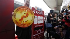 Ken Lo, éf burzy ANXBTC pózuje vedle bitcoinového bankomatu.