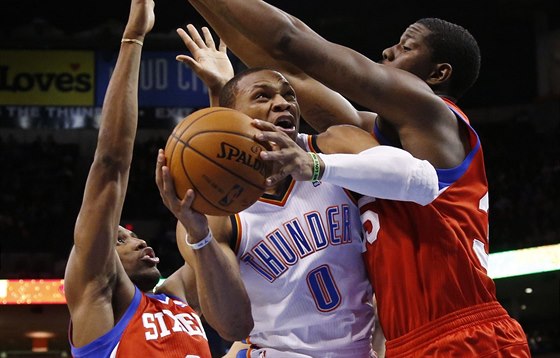 Russell Westbrook (uprosted) z Oklahomy elí ataku Henryho Simse (vpravo) a...