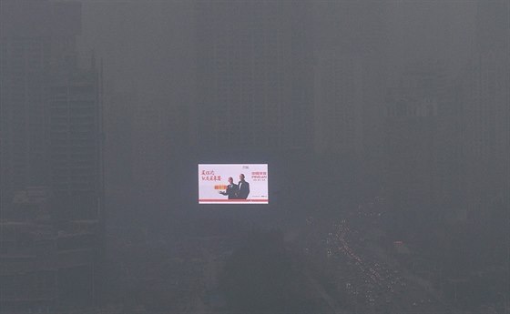Ve smogem zahaleném ínském mst en-jang záí jen elektronický billboard na...