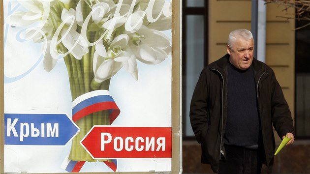 Mu prochz v Simferopolu kolem plaktu s npisy Krym a Rusko. (12. bezna 2014)