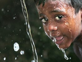 OSV̎ENÍ. Srílanský chlapec si oplachuje obliej u veejného zdroje vody v...