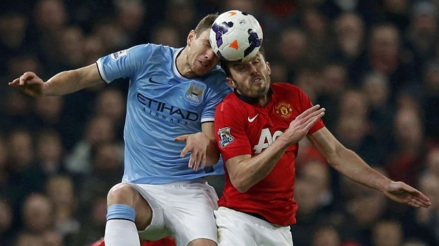 HLAVY V SOB. Edin Deko z Manchesteru City a Michael Carrick z Manchesteru United ve vzdunm souboji.  