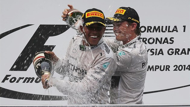 ZASLOUEN SPRCHA. Rozjaen jezdci stje Mercedes ovldli Velkou cenu Malajsie. Vlevo je vtz Lewis Hamilton, ampask na nj lije tmov kolega Nico Rosberg, kter dojel druh.