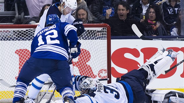 Brank Ondej Pavelec z Winnipegu likviduje anci Masona Raymonda z Toronta. Pomh mu obrnce Paul Postma.