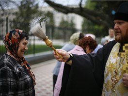 Duchovní ve východoukrajinském Slavjansku na Bílou sobotu kropí vící svcenou...