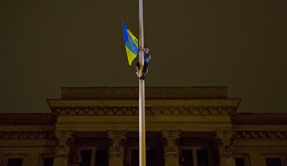 Stoupenc nové vlády v Kyjev ví ukrajinskou vlajku ped vypálenou budovu...