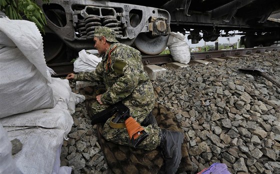 Proruský separatista se kryje za vlakem nedaleko Slavjansku (12. kvtna 2014)