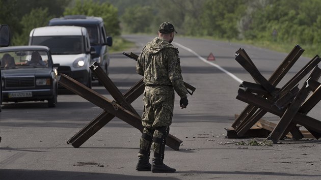 Prorusk ozbrojenec stoj na silninm ztarasu nedaleko Slavjansku na trase do Charkova (19. kvtna 2014).