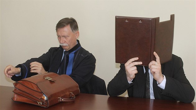 Obalovaný Miroslav Zeman si u soudu schovával obliej za desky s dokumenty.