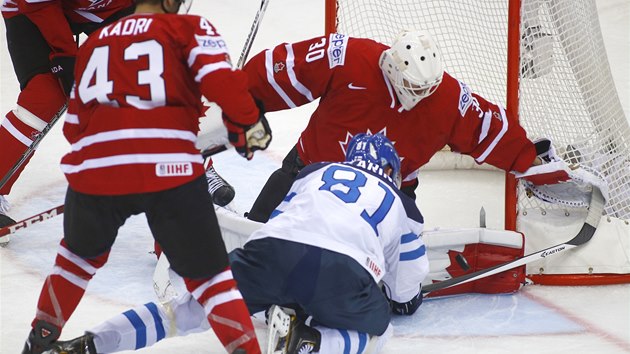 Finsk hokejista Irio Pakarinen se pokou procpat puk za kanadskho branke Bena Scrivense.  