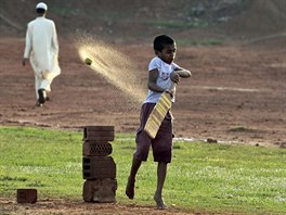 MALÝ KRIKET. Bangladéský muslim prochází kolem malého chlapce hrajícího v zemi...