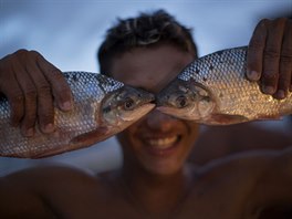 RYBÍ OI. Mladý obchodník pózuje s dvojicí ryb na rybím trhu v brazilském mst...