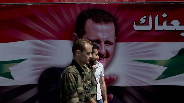 Syrt vojci prochz kolem autobusu s portrtem autoritativnho prezidenta Asada bhem probhajcch voleb v Damaku (3. ervna 2014)