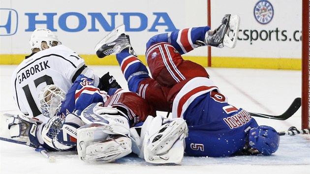 TV NA LED. Dan Girardi z New York Rangers se sna pomoci svmu branki Henriku Lundqvistovi a zastavit puk ped brankovou rou, Marin Gbork z Los Angeles vsed sleduje, jak to dopadne. 