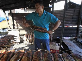 Mu na Filipínách pipravuje uzené tuáky, aby je prodal na trhu bhem svatého...