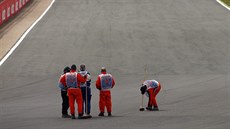 Poadatelé uklízejí tra po havárii Kimiho Räikkönena ve Velké cen Británie.