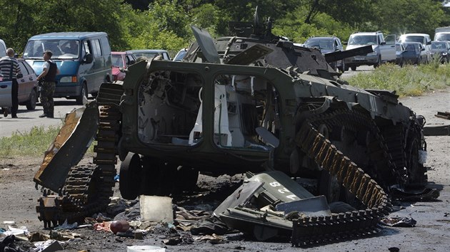 Lid ekaj ve svch autech na cest do Slavjansku, v poped je znien rusk ozbrojen vozidlo (10. ervence 2014).