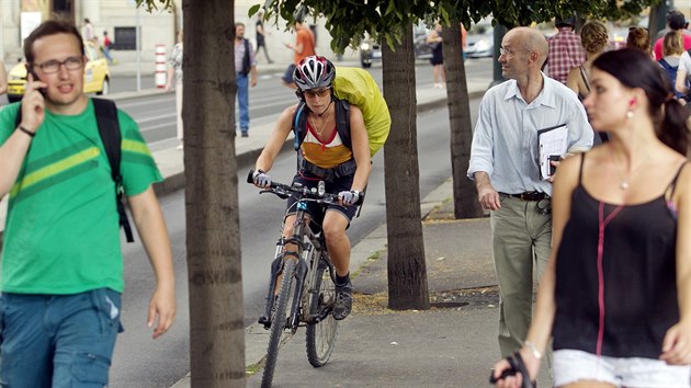 Cyklistka klikuje mezi chodci na Smetanov nbe v Praze