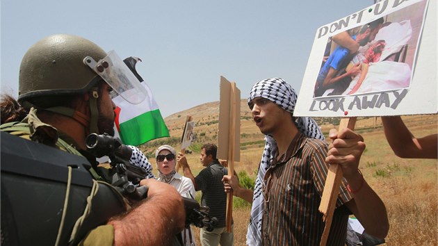 Palestint demonstranti dr fotografie obt izraelskch nlet a dohaduj se s izraelskm vojkem na zem psma Gazy. (13. ervence 2014)