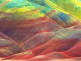 Vypadá to jako batika. Zvlnné kopce jakoby byly nastíkány pruhy barev, které...