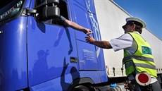 Řidič kamionu podává doklady policistovi při silniční kontrole u Býkve na... Řidič kamionu podává doklady policistovi při silniční kontrole u Býkve na...