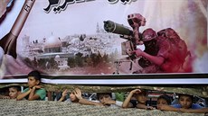 Palestinské dti se koukají pod plakátem podporující palestinská hnutí v Rafáhu...