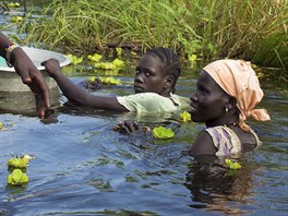 OBCHOD. Afrianky z kmene Nuer se vracejí z celodenní cesty hlubokým bahnem a...