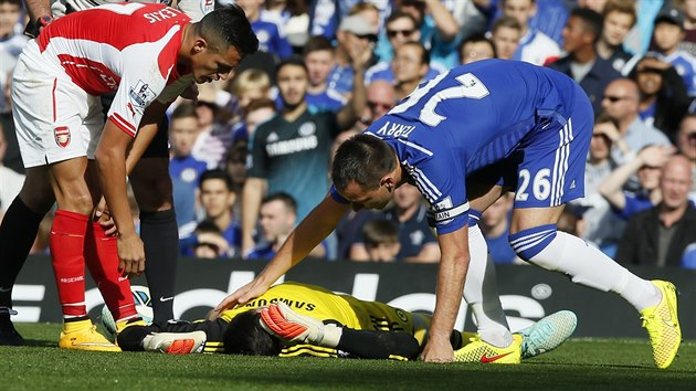 BUDE V PODKU? Thibaut Courtois (lec), brank Chelsea, sice nastoupil do londnskho derby s Arsenalem od prvn minuty, zpas ale nedochytal. V prvnm poloase utrpl srku s Alexisem Snchezem (v ervenm), po kter byl nucen stdat, a na hit se tak dostal esk glman Petr ech.