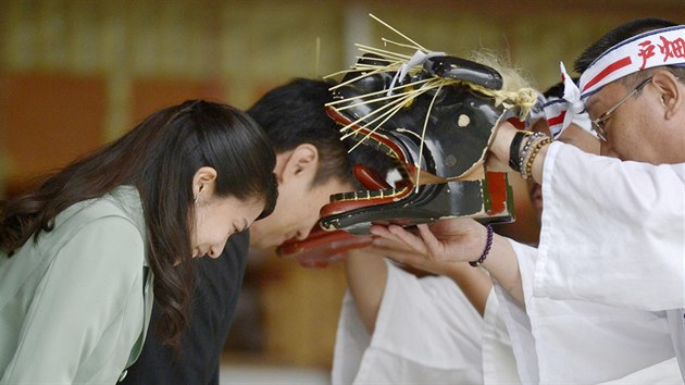 Japonsk princezna Noriko a Kunimaro Senge si nechvaj pokousat hlavy maskou lva, co jim m pinst zdrav (Izumo, 5. jna 2014).