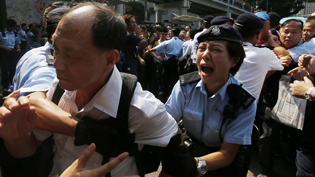 Policistka se sna zastavit rozzuenho odprce prodemokratickch aktivist v Hongkongu (13. jna 2014).