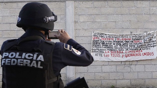 Mexick policista z federlnch jednotek si fot banner na zdi ve mst Iguala, na kterm se pe o obav, e v Iguale zane zabjen, pokud tam nebudou dn policist. Celkem 22 policist bylo zateno kvli podezen ze stelby na autobus se studenty.