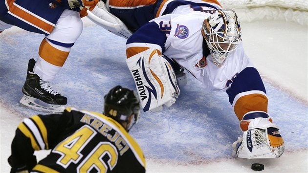 Brank Chad Johnson z Islanders se vrh po puku, na kter hladov hled i tonk Bostonu David Krej.