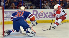 Jií Tlustý z Caroliny se ítí na branku Edmontonu, kterou hájí Ben Scrivens.