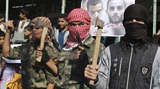 V Rafáhu maskovaní palestintí bojovníci se sekerami, noi a zbranmi oslavují...