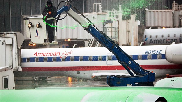 Pracovnk letit stk rozmrazovac tekutinu na letadlo spolenosti Eagle jet v New Yorku. (26. listopadu 2014)