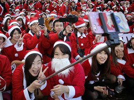 People dressed in Santa costumes take "selfies" during the Tokyo Santa Run at...