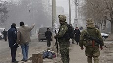 Ukrajintí vojáci steí ulici v Mariupolu, poblí tlo obti raketového útoku...