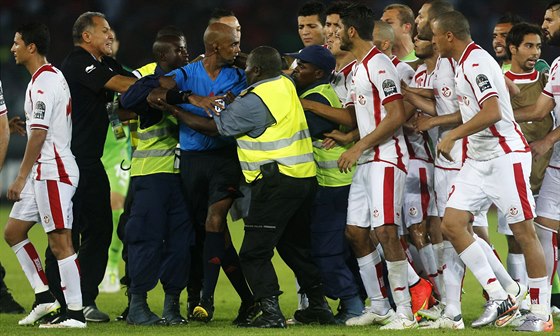 Tunití fotbalisté se snaí napadnou sudího Rajindraparsada Seechurna po...