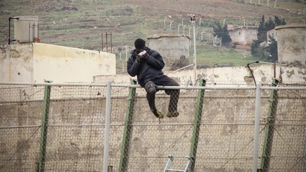 Africk uprchlk na plotu mezi Melillou a Marokem pojd sendvi, kter mu hodil panlsk pohranink. (10. nora 2015)