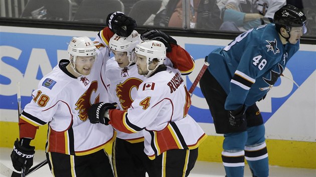 Matt Stajan (18), Mason Raymond (21) a Kris Russell (4) oslavuj trefu Calgary proti San Jose, vpravo zklaman Tom Hertl.