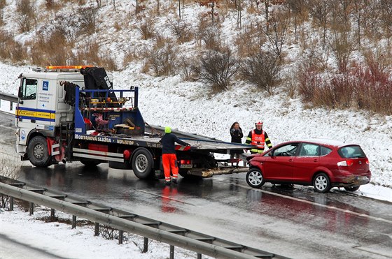 Odtahovka nakládá jedno z devíti vozidel, která se ráno srazila na silnici R6...