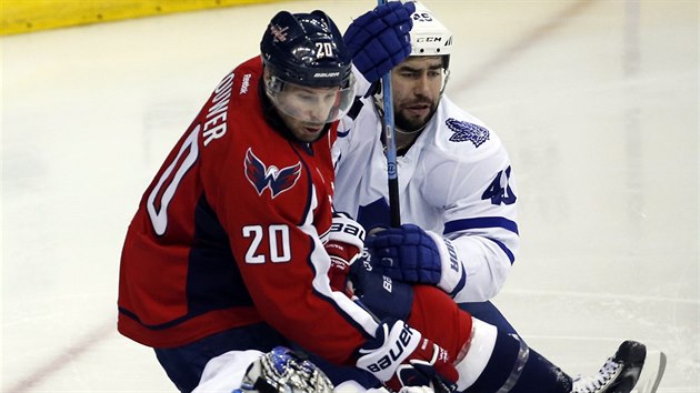 Washingtonsk Troy Brouwer (v ervenm) se sna prosadit pes brncho Romana Polka z Toronta ped branke Jamese Reimera.