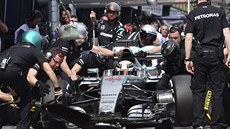 Lewis Hamilton a jeho vz pod hbitýma rukama mechanik.