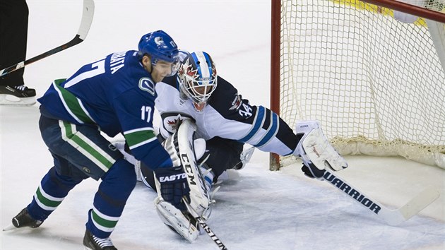 Radim Vrbata z Vancouveru zkou dostat puk a do branky Michaela Hutchinsona z  Winnipegu.