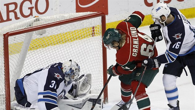 Ondej Pavelec hld branku Winnipegu v utkn s Minnesotou, atakuje ho Mikael Granlund.