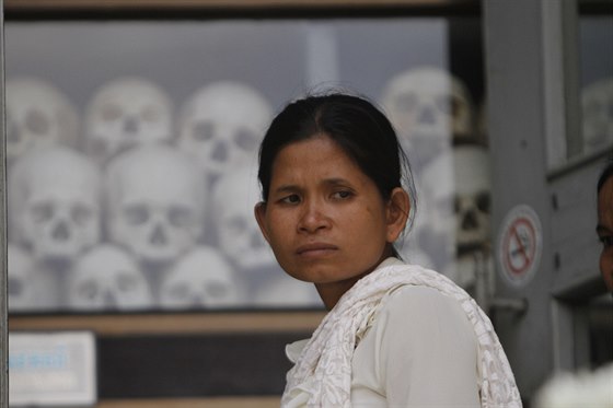 Mladá ena stojí v muzeu u nkolika set lebek a kostí zavradných Kambodan....